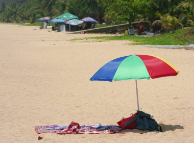 Phuket, Tayland-31 Mart 2016: Kimliği belirsiz insanlar güneşleniyor ve Karon Sahili 'nde ağaçların yanında oturuyor