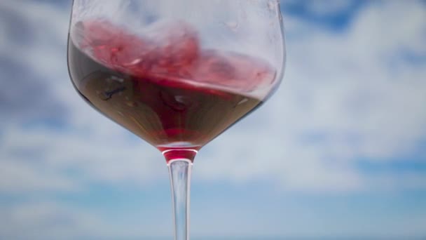 Ένα Ποτήρι Κόκκινο Κρασί Στροβιλίζεται Αργή Κίνηση Σύννεφα Στο Παρασκήνιο — Αρχείο Βίντεο