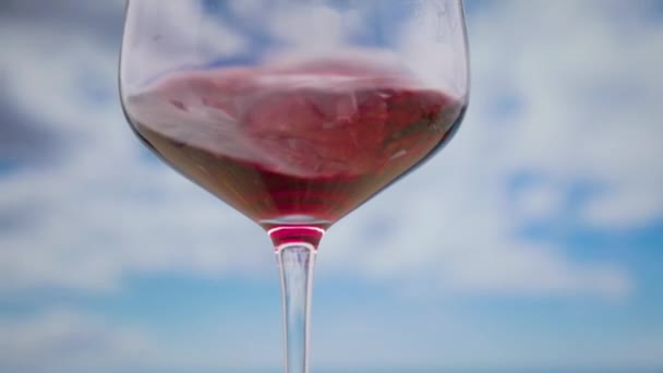 Una Copa Con Vino Tinto Girando Cámara Lenta Con Nubes — Vídeo de stock