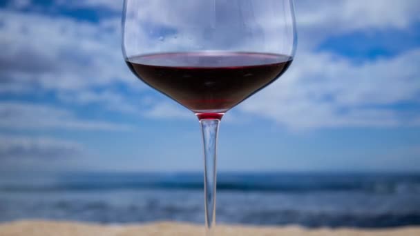 Ένα Ποτήρι Κόκκινο Κρασί Μια Παραλία Κινούμενα Σύννεφα Στο Παρασκήνιο — Αρχείο Βίντεο