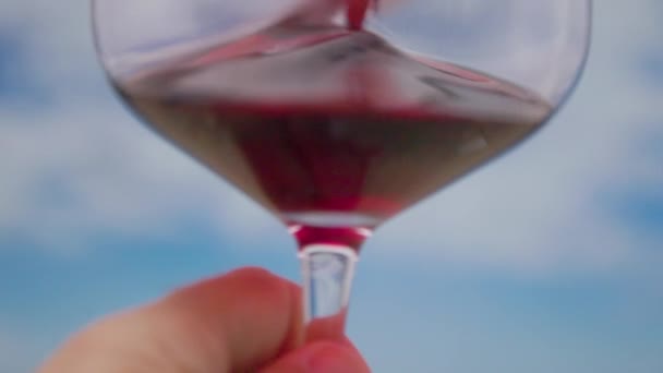 Kırmızı Şaraplı Bir Bardak Ağır Çekimde Döndürülmüş Arkasında Bulutlar Var — Stok video