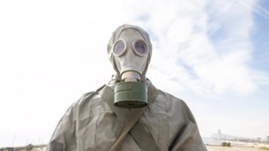 Kimyasal gaz saldırısı sırasında gaz kıyafeti giymiş bir adam kameraya bakıyor.