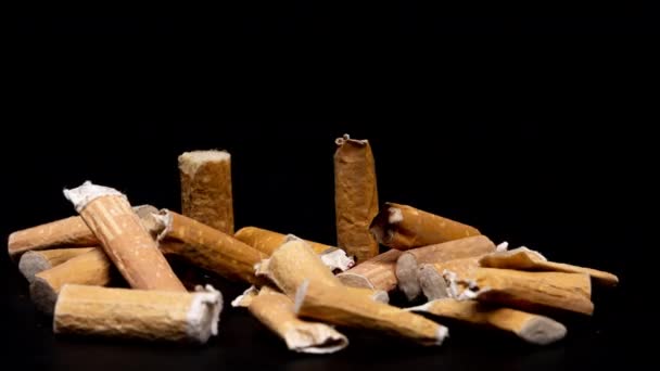 黒い背景に積もっているタバコの吸い殻の動きを止める — ストック動画