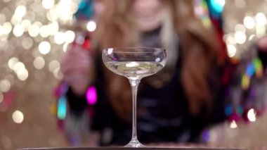 A stylish and pretty woman dancing dancing behind a glass of champagne