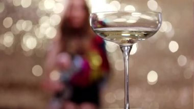 A stylish and pretty woman dancing behind a glass of champagne