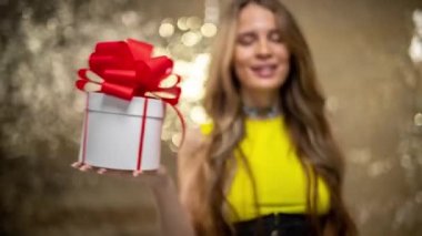A beautiful woman holding a gift box with red bow 