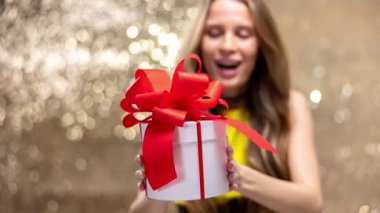 A beautiful woman holding a gift box with red bow 