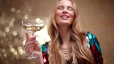 A stylish and pretty woman dancing holding a glass of champagne