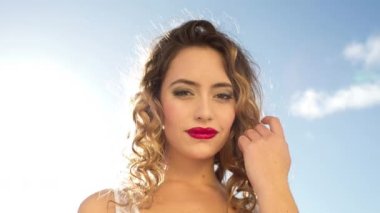 A beautiful woman posing and dancing outside against blue sky
