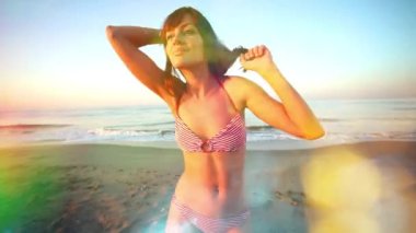 A beautiful woman in bikini dancing and posing on the beach 