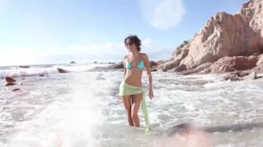A beautiful woman in bikini dancing and posing on the beach 