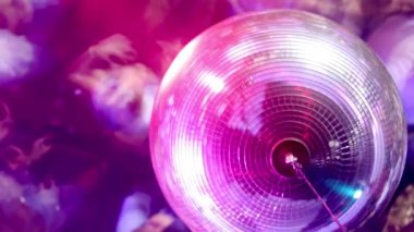 A view looking down past a disco ball to a crowd in a nightclub