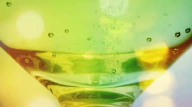 Champagne bubbling in a glass with colourful soft lights 