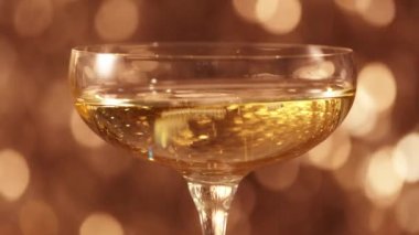 Champagne in a glass against sparkling golden background