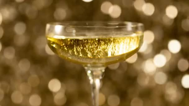 Champagne Een Glas Tegen Sprankelende Gouden Achtergrond — Stockvideo