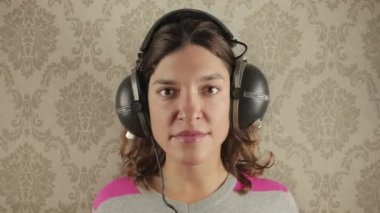 Beautiful female with changing vintage headphones against funky wallpaper