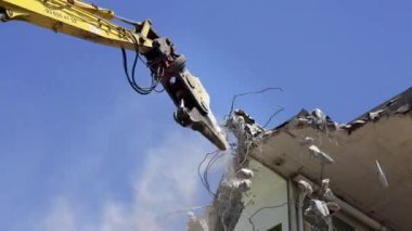 Ağzı olan bir vinç bir binayı yıkıyor, dinozorun yemek yemesine benziyor. 