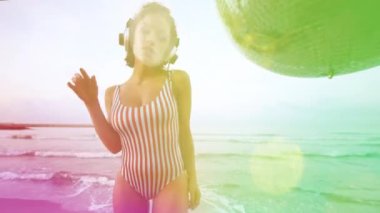 Sahilde bikinili ayna toplarıyla dans eden güzel bir kadın.