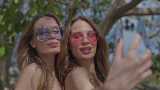 Identiska Tvillingkvinnor Poserar För Selfies Med Mobiltelefon — Stockvideo