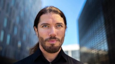 Arka planda ofis binaları olan genç bir adam.