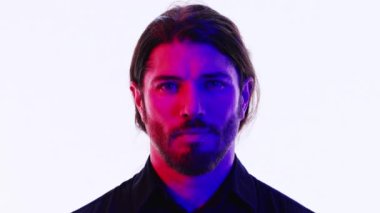 Genç bir adam kırmızı ve mavi karışık ışıklarla kameraya bakıyor. İyi bir moda ya da teknoloji konsepti