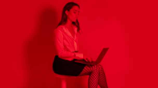 赤い光の椅子の上でノートパソコンを操作する女性 — ストック動画