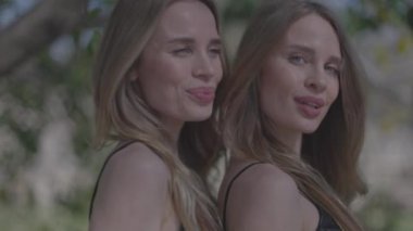 Siyah kıyafetlerle poz veren ikiz kadınlar.