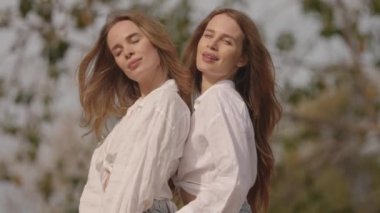 Parktaki duvarda oturan tek yumurta ikizi kadınlar.