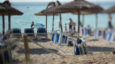 Mallorca 'da güverte sandalyeli bir plaj fotoğrafı. Bu odak dışı insanlarla eğik bir odak çekimi. 