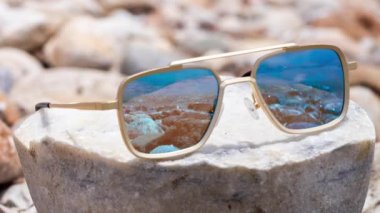 Sahilde yansıyan aynalı güneş gözlükleri denizi yansıtıyor.