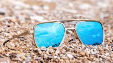 Sahilde yansıyan aynalı güneş gözlükleri denizi yansıtıyor.