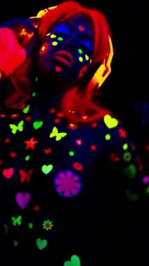 Ultraviyole floresan giyinen ve dikey makyaj yapan havalı dans eden bir kadın.