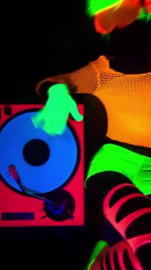 Havalı bir DJ kadın UV floresan giyiniyor ve dikey makyaj yapıyor.