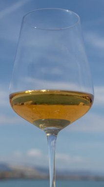  Güneşin doğuşunda ya da batışında arka planda beyaz şarap ve köpüklü deniz ve gökyüzü olan bir bardak.