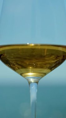  Güneşin doğuşunda ya da batışında arka planda beyaz şarap ve köpüklü deniz ve gökyüzü olan bir bardak.