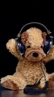 Bir stop motion oyuncak ayısı. Kulaklık takıyor. Dikey pikaplarda DJ 'lik yapıyor.