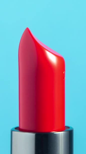 明るい色の口紅のクローズアップ映像は 垂直フォーマットで明白な白い背景に対して回転する ストック映像