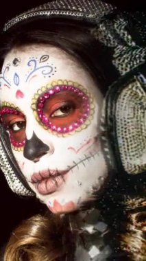 Özel olarak tasarlanmış kafatası şekerlemeleri olan güzel bir kadın. Ölü yüzünün Meksika günü dikey olarak makyaj yapıyor.