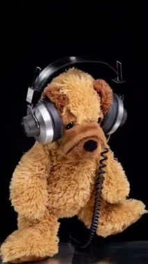 Bir stop motion oyuncak ayısı. Kulaklık takıyor. Dikey pikaplarda DJ 'lik yapıyor.