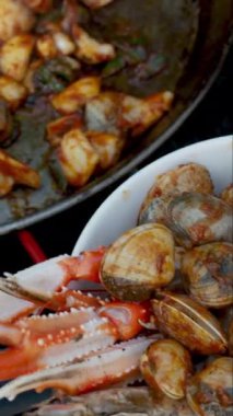 Şef metal tavada bileşenleri karıştırıyor, geleneksel İspanyol enginarlı paella yapıyor.