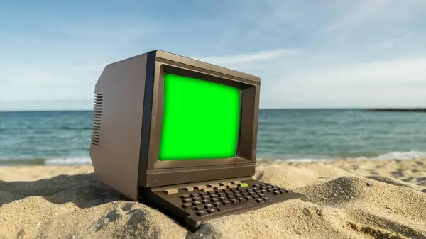 緑のスクリーンが付いているビーチのレトロコンピュータ ロイヤリティフリーのストック写真