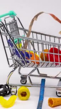 Dikey biçimde beyaz zemin üzerinde bir alışveriş vagonunda plastik çöplerin ve atıkların makro duraklama hareketi birikiyor
