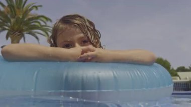 Yüzme havuzunda yüzen küçük bir çocuk.