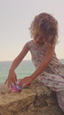 Dikey bir duvarda çiçek toplayan havalı küçük bir kız.