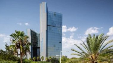 Barselona aynalı cam gökdelen, gökyüzünde bulutlar ve palmiye ağaçları esen rüzgar.