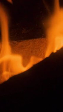 Dikey bir şöminede yanan odun ateşinde alevlerin yakın çekimi