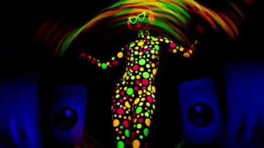 Ultraviyole floresan giyinen ve hoparlörlü makyaj yapan havalı dans eden bir kadın.