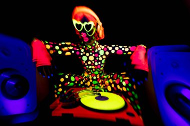 A cool dancing woman wearing UV fluorescent clothing and makeup with audio speakers clipart