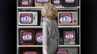 Genç kız ekranda gözleri olan bir televizyon bankasını izliyor.