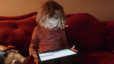 Küçük bir kız karanlık bir odada ekranın ışığıyla oyun oynar ya da tablet bilgisayar izler. 